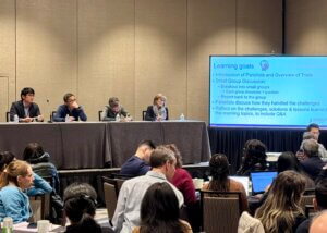 A photo from the 2024 AcademyHealth D&I Workshop showing panelists at a dais answering questions from workshop participants.